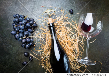 A bottle of red wine with grapes 44003701