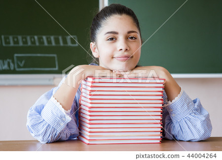 Smiling girl sits against blackboard in classroom 44004264