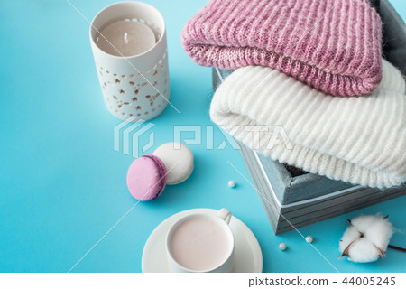 Knitted hats, cotton sprigs, macaroons close-up on a white Knitted hats, cotton sprigs, macaroons close-up on a white 44005245