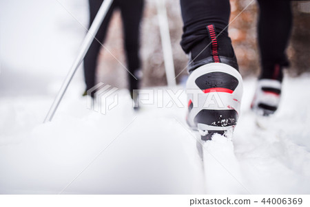 An unrecognizable couple cross-country skiing in winter. An unrecognizable couple cross-country skiing in winter. 44006369