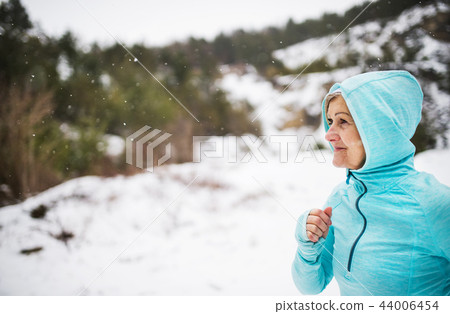 Happy senior woman jogging in winter nature. Happy senior woman jogging in winter nature. 44006454
