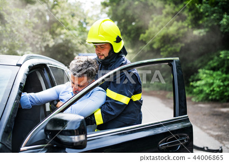 A firefighter getting an unconscious man out of the car after an accident. 44006865