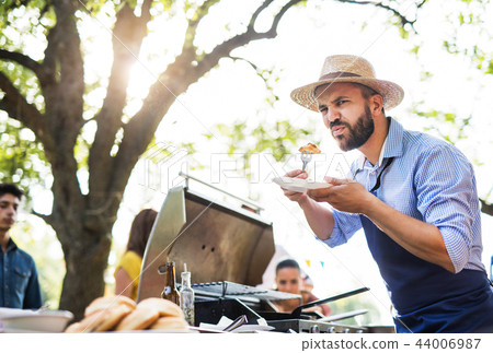 A mature man with family and friends cooking and serving food on a barbecue party. 44006987