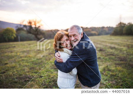 Senior couple hugging in an autumn nature at sunset. Senior couple hugging in an autumn nature at sunset. 44007016