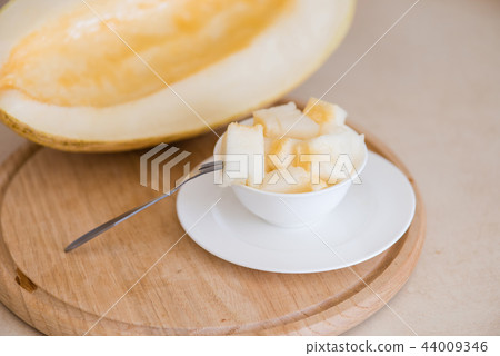 Cutted melon cubes on kitchen cutting board Cutted melon cubes on kitchen cutting board 44009346