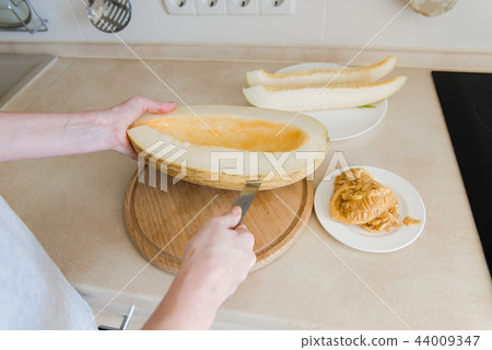 Woman cut melon and clean from seeds Woman cut melon and clean from seeds 44009347