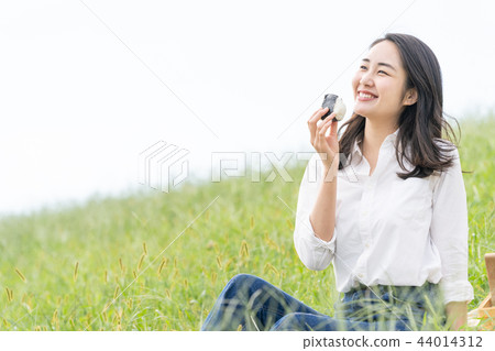 A woman who eats a rice ball A woman who eats a rice ball 44014312