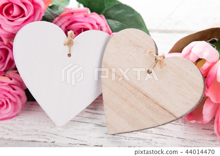 Flowers composition for Valentine's, Mother's or Women's Day. Pink flowers with wooden hearth on old white wooden background. 44014470