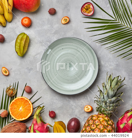 Juicy ripe tropical fruits, pineapple, papaya, mango, pineapple, green palm leaves and empty round 44019924