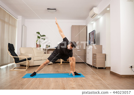 Attractive man trying extended side Yoga poses on his house floor Attractive man trying extended side Yoga poses on his house floor 44023057