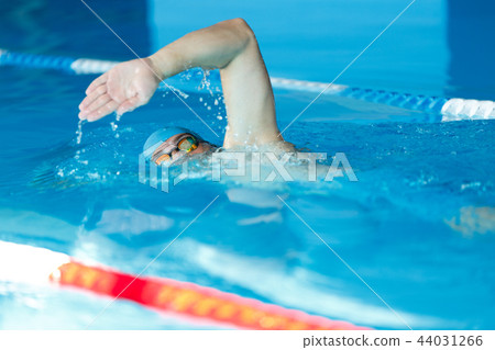 Side view of sports man in blue cap floating on path in pool Side view of sports man in blue cap floating on path in pool 44031266