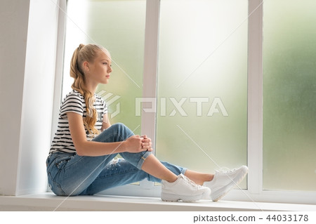 Pretty teenaged girl on window sill profile shot 44033178