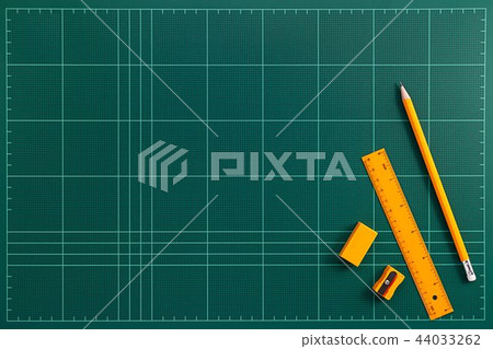 Orange stationery on top the green cutting mat 44033262
