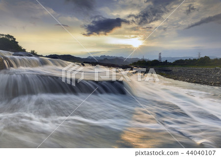 寬廣的河面上,流水在岩石上緩緩流下來形成瀑布模樣. 寬廣的河面上,流水在岩石上緩緩流下來形成瀑布模樣. 44040107