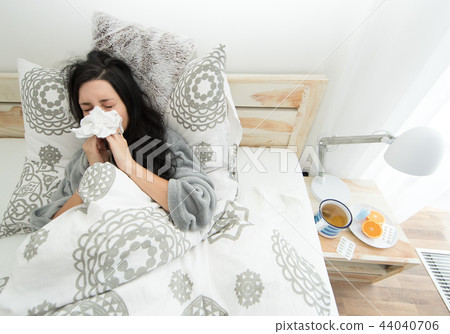 Young woman having flu, blowing her nose. 44040706