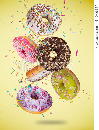 Tasty doughnuts in motion falling on pastel yellow background. 44040935