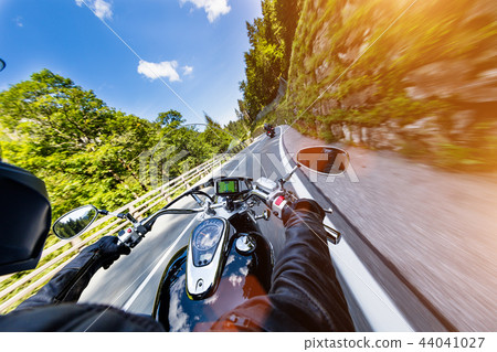 Motorcycle driver riding in Alpine highway, handlebars view, Austria, Europe. 44041027