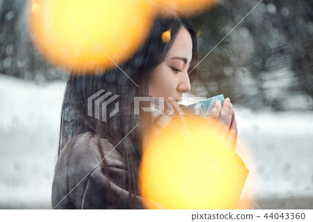 Woman enjoying tea time in the snow Woman enjoying tea time in the snow 44043360