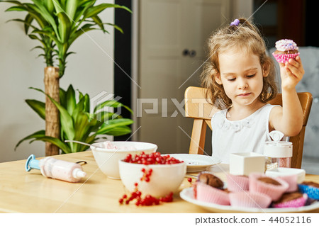 girl in a white dress decorates and eats a delicious cupcakes 44052116