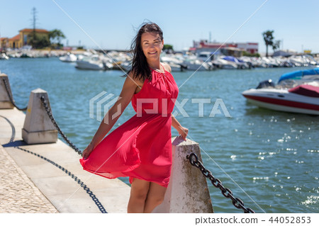 Girl in red dress posing on the beach in a marina in Faro. Girl in red dress posing on the beach in a marina in Faro. 44052853