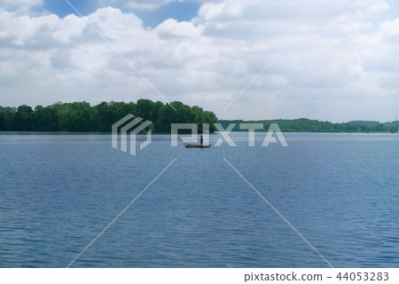 Fisherman in a boat in the middle of a lake Fisherman in a boat in the middle of a lake 44053283