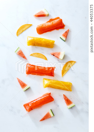 Healthier pop ice popsicles in a vacuum sealer with fruits slice on light marble bacground, flat lay Healthier pop ice popsicles in a vacuum sealer with fruits slice on light marble bacground, flat lay 44053375