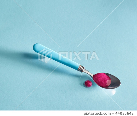 Healthy organic smoothies of red berries in a spoon on a glass blue background. 44053642