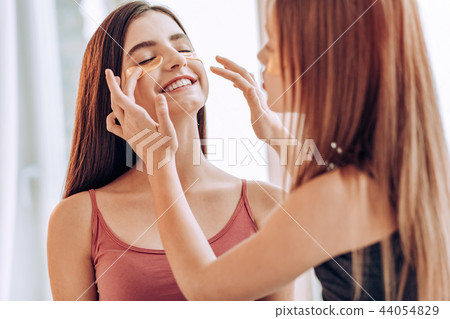 Positive delighted teenagers doing local face mask Positive delighted teenagers doing local face mask 44054829