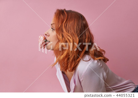 Studio fashion photo of beautiful young woman with flowers in her mouth isolated on pink 44055321