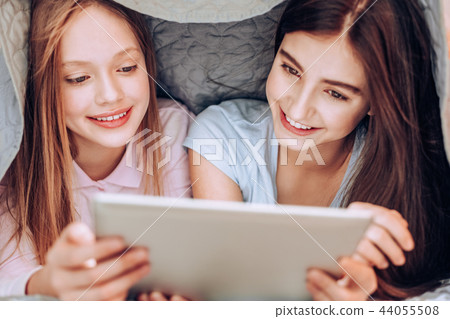 Charming schoolgirls staring at screen of their gadget Charming schoolgirls staring at screen of their gadget 44055508