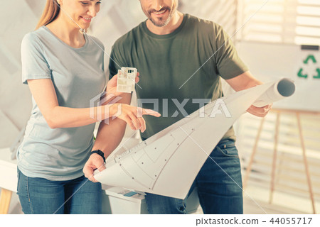 Pleased male person helping his pretty colleague 44055717