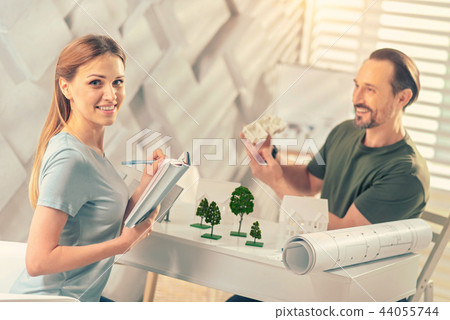 Cheerful female person writing notices in copybook 44055744