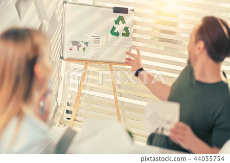 Competent engineer pointing at recycling sign on desk Competent engineer pointing at recycling sign on desk 44055754