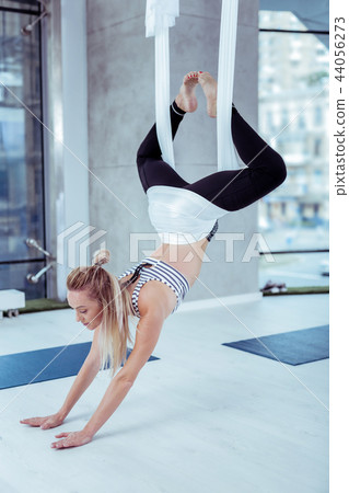 Attentive nice woman swinging from ceiling in studio 44056273