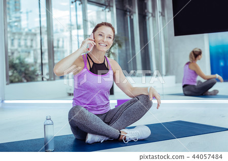 Joyful mature woman communicating on phone during training 44057484