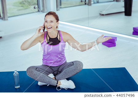 Enthusiastic mature woman talking on phone during training 44057496