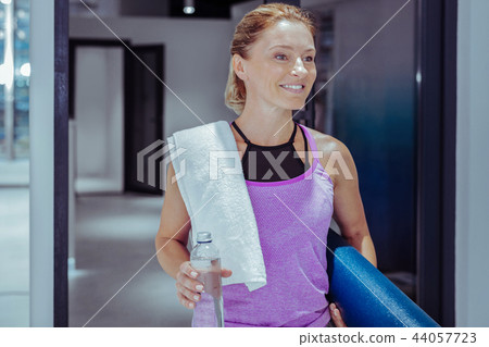 Happy mature woman entering gym with water Happy mature woman entering gym with water 44057723