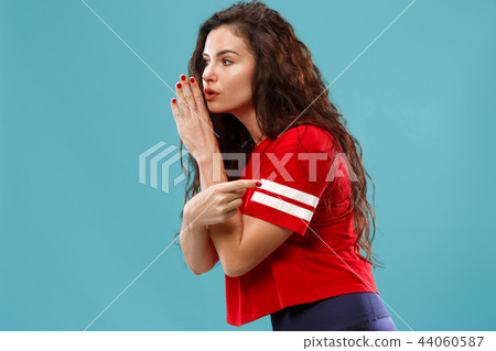 The young woman whispering a secret behind her hand over blue background The young woman whispering a secret behind her hand over blue background 44060587