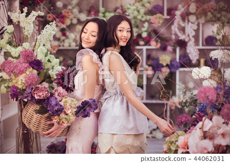 Beautiful asian women florists happy working in flower store with a lot of spring flowers Beautiful asian women florists happy working in flower store with a lot of spring flowers 44062031
