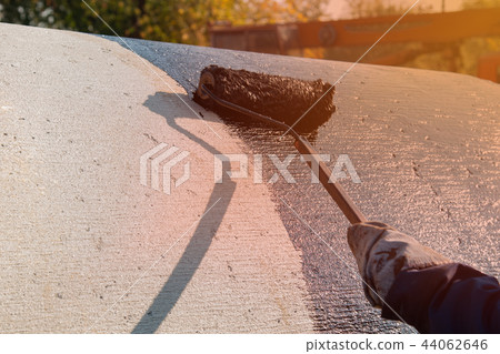 Roofer worker painting black coal tar or bitumen 44062646