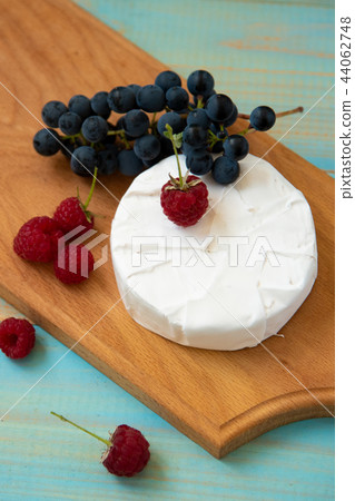 cheese camembert with raspberries and grapes on table 44062748