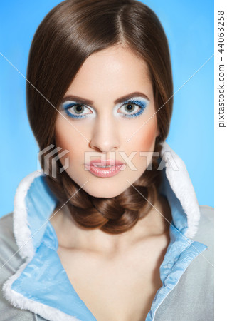 Beautiful young girl in a blue fur coat with a white collar with bright make-up and blue eyes Beautiful young girl in a blue fur coat with a white collar with bright make-up and blue eyes 44063258