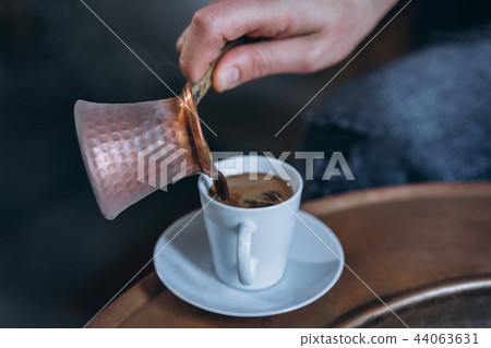Man's hand pours coffee into a cup Man's hand pours coffee into a cup 44063631