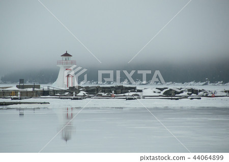 Lion's Head lighthouse with melting ice on the bay reflecting an 44064899