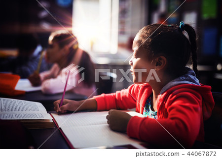 Attentive schoolgirl doing her homework in classroom 44067872