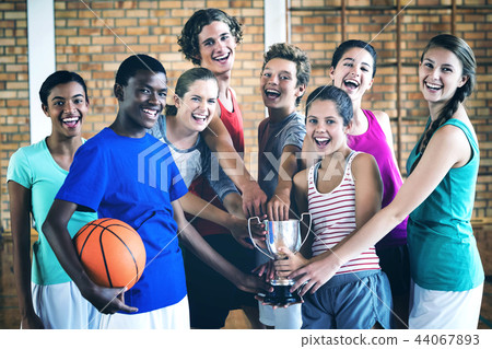 Smiling high school kids holding trophy in basketball court 44067893