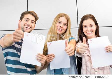 Composite image of students holding up exam and doing thumbs up 44068622