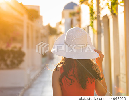 Santorini travel tourist brunette woman in red dress visiting famous white Oia village. 44068923