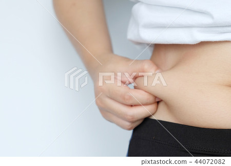 Side of woman hand catching fat body belly paunch 44072082