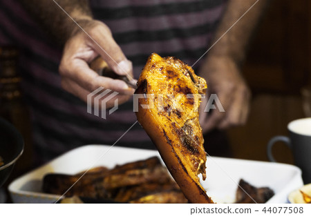 The man lays juicy roasted pieces of meat on dish The man lays juicy roasted pieces of meat on dish 44077508